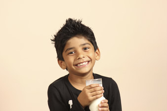 Young, Smiling Boy Holding a Cup of Milk