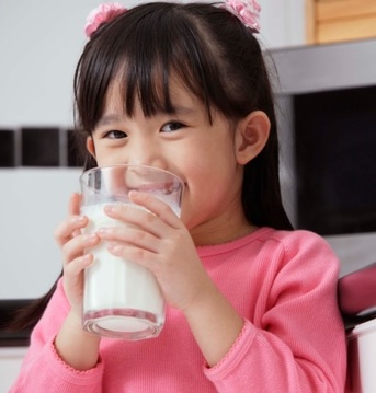 Smiling girl drinking glass of milk