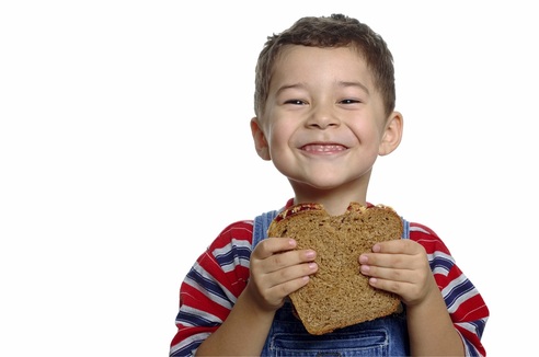 Young Boy Happily Eating a Whole Grain Slice of Bread