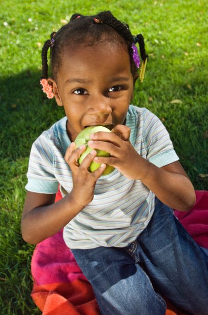 Young Girl Enjoying a Granny Smith Apple in the Sun